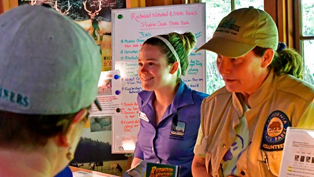 An image of a young and adult woman at a visitor center desk. 