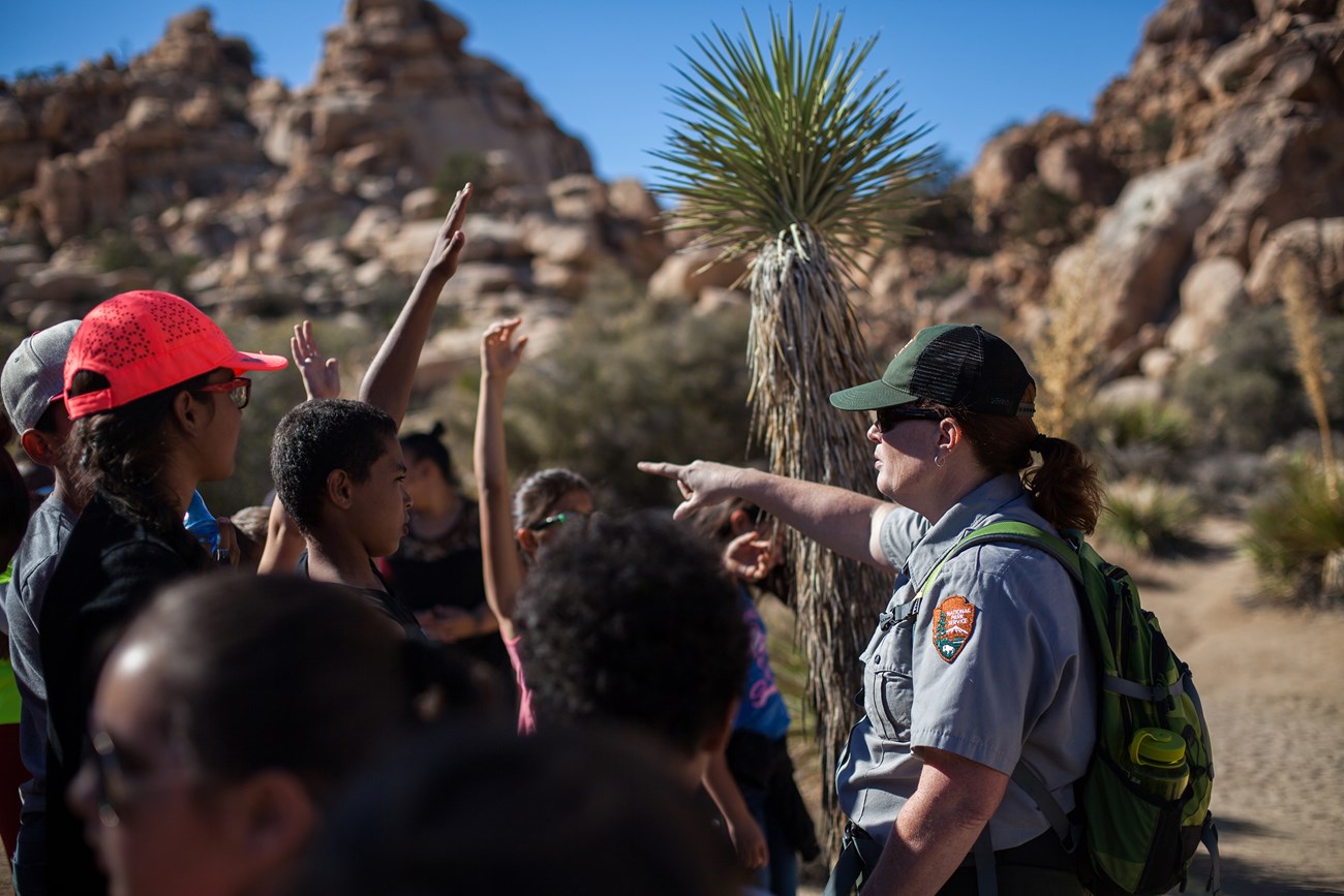 Students talk outside in the Joshua Tree Wilderness. Students talk outside with a park ranger.